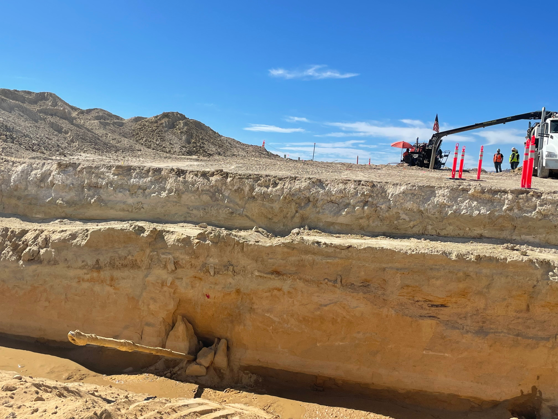 Deep excavation exposing native rock layers alongside the drilling operation