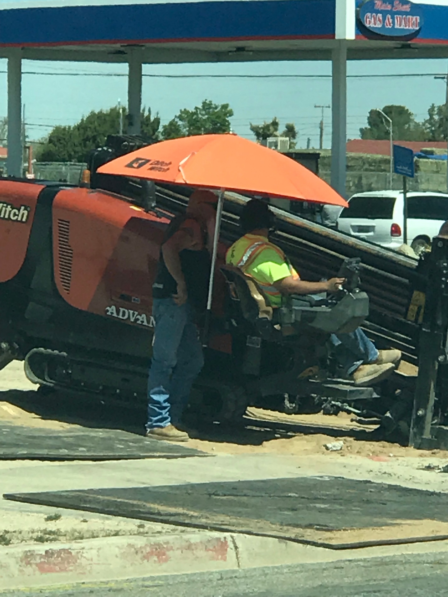 Ditch Witch rig with orange umbrella boring curbside on a Victor Valley main street